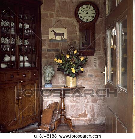 Antique clock on stone wall above sculpture head on Victorian table in small hall with antique corner dresser View Large Photo Image Stock Photo - Antique clock on stone wall above sculpture head on Victorian table in small hall with antique corner dresser. Fotosearch