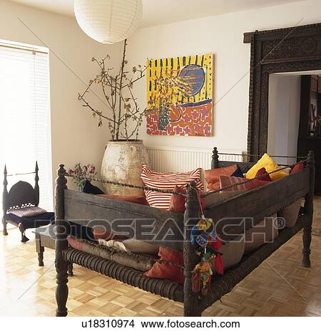 Antique Indonesian day bed and woodblock flooring in modern livingroom with picture above large terracotta pot in the corner of the room View Large Photo Image Picture - Antique Indonesian day bed and woodblock flooring in modern livingroom with picture above large terracotta pot in the corner of the room . Fotosearch