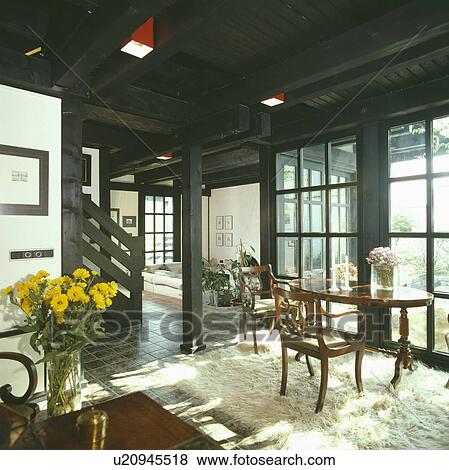 Antique table and chairs on sheepskin rug in seventies openplan dining room with black ceiling View Large Photo Image Stock Photo - Antique table and chairs on sheepskin rug in seventies openplan dining room with black ceiling. Fotosearch