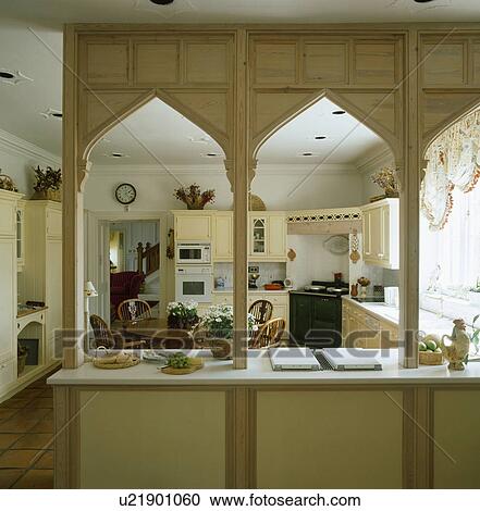 Stock Image - Arched wooden Gothic style divider on worktop in neutral country kitchen. Fotosearch