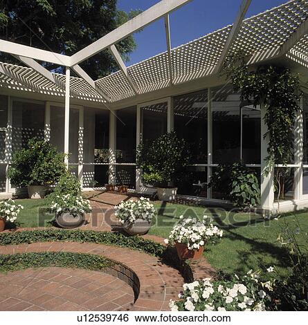 Architectural trellis over circular patio with containers of white flowers View Large Photo Image Stock Photograph - Architectural trellis over circular patio with containers of white flowers. Fotosearch