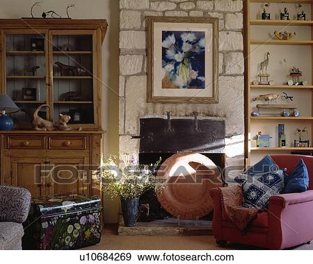 Stock Photo - Armchair beside fireplace in rough stone wall in traditional living room. Fotosearch