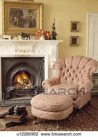 Stock Image - Armchair beside fireplace in traditional living room. Fotosearch