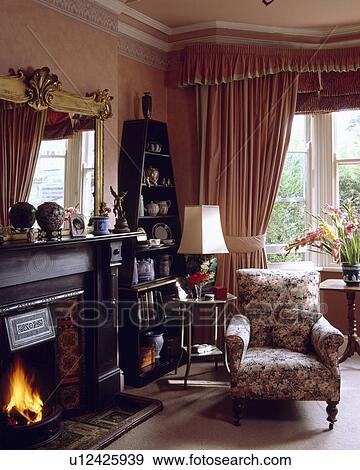 Armchair beside fireplace in traditional pink living room View Large Photo Image Stock Photo - Armchair beside fireplace in traditional pink living room. Fotosearch