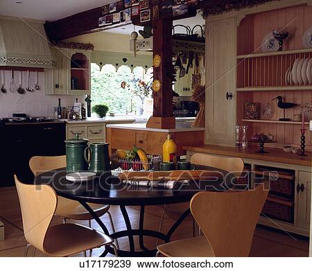 Stock Photo - Arne Jacobsen Ant chairs and circular table in front of dresser in openplan traditional kitchen dining room. Fotosearch