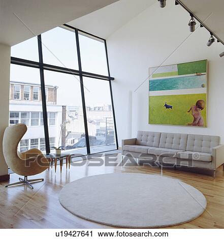 Stock Image - Arne Jacobsen Egg chair in modern loft converion living room with white circular rug. Fotosearch