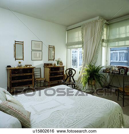 Bamboo chests-of-drawers and Bed with white lace cover in white bedroom with pastel green blinds and white curtains View Large Photo Image Stock Photograph - Bamboo chests-of-drawers and Bed with white lace cover in white bedroom with pastel green blinds and white curtains . Fotosearch