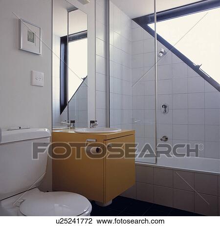 Basin built into fitted yellow vanity unit between toilet and shower in small modern white bathroom View Large Photo Image Stock Image - Basin built into fitted yellow vanity unit between toilet and shower in small modern white bathroom. Fotosearch