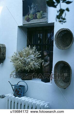 Stock Image - Baskets on wall beside alcove with dried flowers. Fotosearch