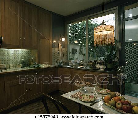 Beaded lampshade above place settings on table in wooden kitchen View Large Photo Image Stock Photo - Beaded lampshade above place settings on table in wooden kitchen . Fotosearch
