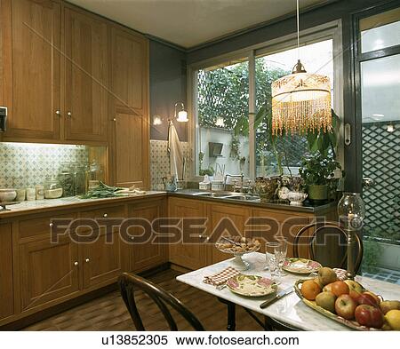 Beaded lampshade above place settings on table in wooden kitchen View Large Photo Image Stock Photography - Beaded lampshade above place settings on table in wooden kitchen . Fotosearch