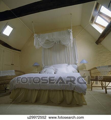 Bed with white canopy and blue striped duvet in country loft conversion bedroom View Large Photo Image Stock Image - Bed with white canopy and blue striped duvet in country loft conversion bedroom . Fotosearch
