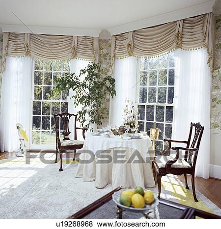 Beige ruched blinds and white curtains at tall windows in eighties diningroom with beige cloth on circular table View Large Photo Image Stock Photo - Beige ruched blinds and white curtains at tall windows in eighties diningroom with beige cloth on circular table. Fotosearch
