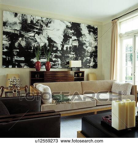 Stock Image - Beige suede sofa and large black+white painting in modern living room. Fotosearch