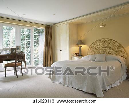 Berige linen bedcover on bed with patterned headboard in neutral bedroom with white carpet View Large Photo Image Stock Image - Berige linen bedcover on bed with patterned headboard in neutral bedroom with white carpet. Fotosearch