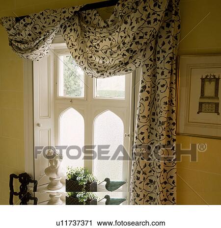 Black And White Patterned Drapes Above Window With White Shutters