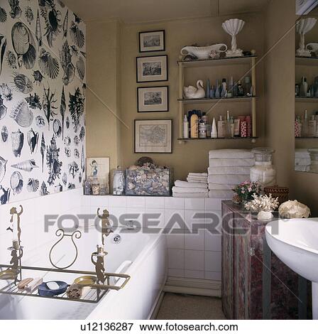 Black and white seashell patterned wallpaper on wall above white bath with brass rack in neutral bathroom View Large Photo Image Stock Photo - Black and white seashell patterned wallpaper on wall above white bath with brass rack in neutral bathroom . Fotosearch