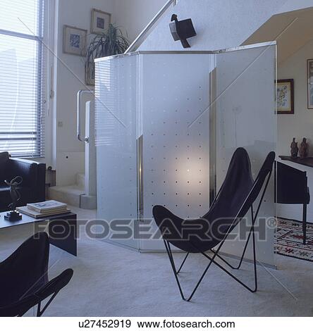 Black butterfly chair in front of glass screen in modern white living room View Large Photo Image Stock Photo - Black butterfly chair in front of glass screen in modern white living room. Fotosearch