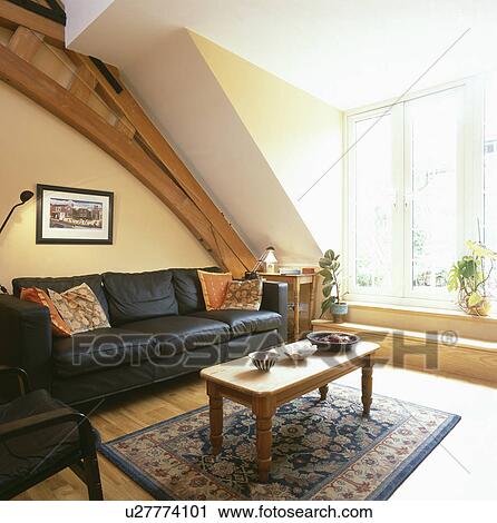 Stock Image - Black leather sofa in attic living room. Fotosearch