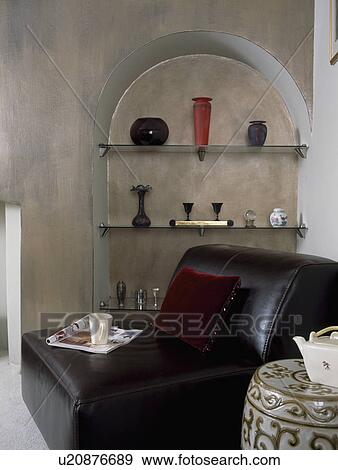 Stock Photo - Black leather sofa in front of alcove with shelves in modern livingroom with distressed paint effect walls. Fotosearch