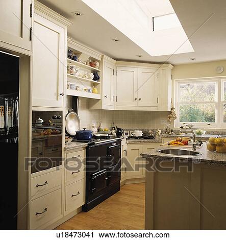 Stock Image - Black oven in white traditional kitchen extension with wooden flooring. Fotosearch