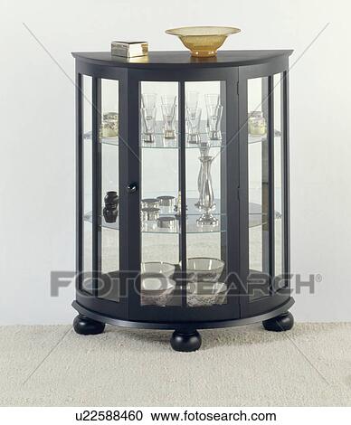 Stock Image - Black semi circular thirties style cupboard with glass shelves and mirrored back. Fotosearch