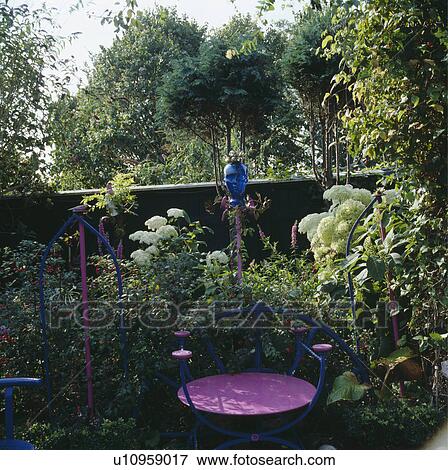 Blue and pink metal chair in front of summer garden border with white hydrangeas and blue glass bauble View Large Photo Image Stock Photo - Blue and pink metal chair in front of summer garden border with white hydrangeas and blue glass bauble. Fotosearch