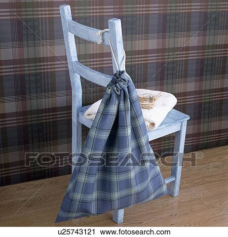 Stock Image - Blue checked laundry bag on pastel blue painted wooden chair. Fotosearch