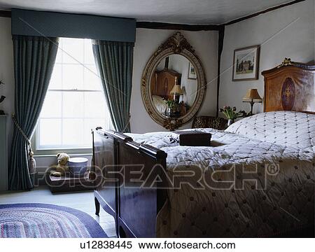 Blue Curtains And Large Gilt Antique Mirror In Traditional Bedroom