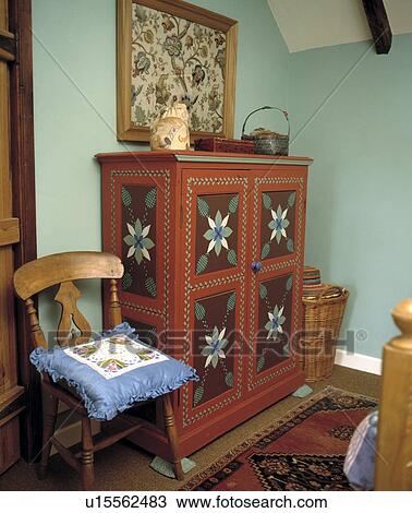Blue cushion on old wooden chair beside decoratively painted cupboard in pale turquoise bedroom View Large Photo Image Stock Image - Blue cushion on old wooden chair beside decoratively painted cupboard in pale turquoise bedroom. Fotosearch