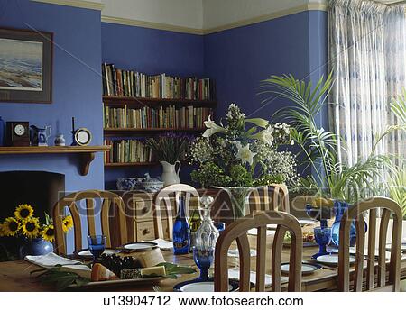 Stock Image - Blue glasses on table in bright blue dining room. Fotosearch