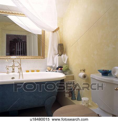 Blue rolltop bath below gilt mirror in attic bathroom with ragging-effect walls View Large Photo Image Stock Photography - Blue rolltop bath below gilt mirror in attic bathroom with ragging-effect walls. Fotosearch