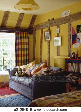 Stock Photograph - Blue sofa in yellow beamed country living room. Fotosearch
