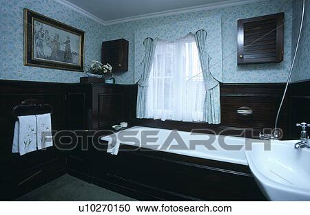 Stock Image - Blue wallpaper and matching curtains above bath in traditional bathroom. Fotosearch