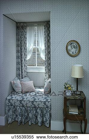 Stock Photography - Blue+white patterned windowseat and curtains in small hall with patterned wallpaper and antique table. Fotosearch