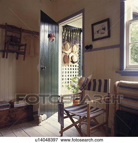 Stock Photo - Blue+white striped director's chair beside open green door in panelled white cottage hall with wooden floor. Fotosearch