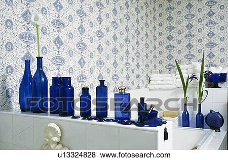 Stock Photo - Blue+white wallpaper and collection of blue bottles on shelf above bath. Fotosearch