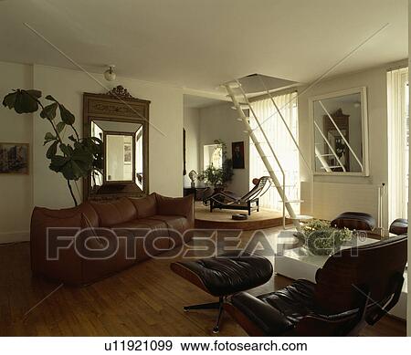 Stock Photo - Brown leather sofa and Charles Eames chaiselongue in modern living room. Fotosearch