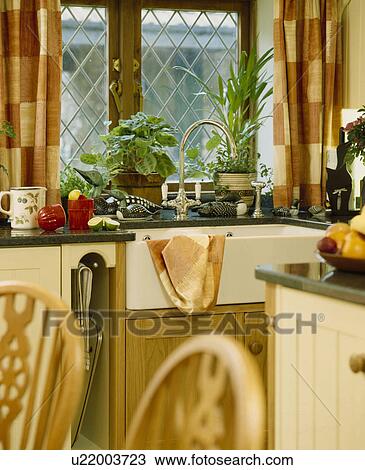 Brown+cream checked curtains at lattice kitchen window with houseplants on window sill above white Butler's sink View Large Photo Image Stock Image - Brown+cream checked curtains at lattice kitchen window with houseplants on window sill above white Butler's sink. Fotosearch