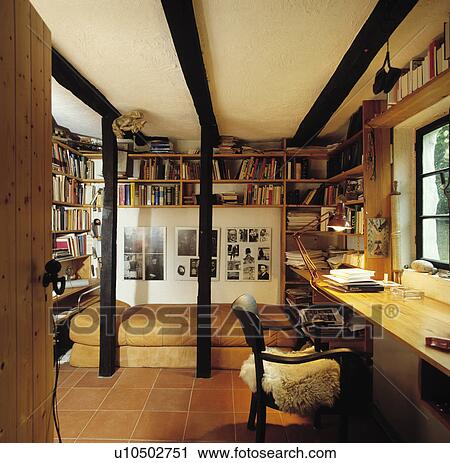 Chair at pine desk in study bedroom with wall shelves above bed with leather cover View Large Photo Image Stock Image - Chair at pine desk in study bedroom with wall shelves above bed with leather cover. Fotosearch