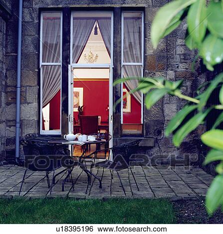 Stock Photograph - Chairs and table on patio in garden in summer. Fotosearch