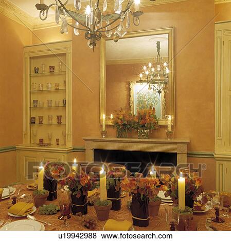 Chandelier above table with floral arrangements lighted candles in pale orange traditional dining room View Large Photo Image Stock Photo - Chandelier above table with floral arrangements lighted candles in pale orange traditional dining room. Fotosearch