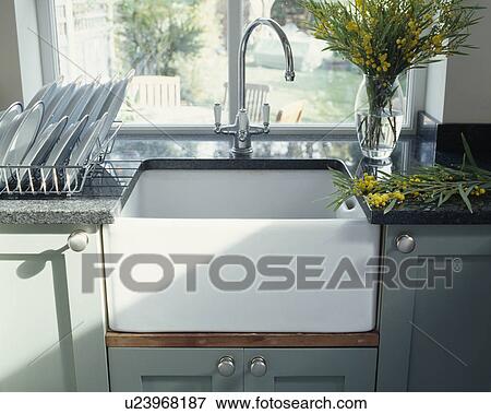Chrome mixer tap with white butler's sink underset in granite worktop with vase of yellow mimosa View Large Photo Image Stock Photo - Chrome mixer tap with white butler's sink underset in granite worktop with vase of yellow mimosa. Fotosearch