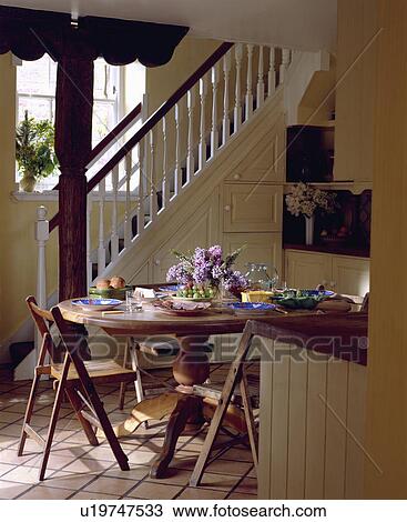 Circular Dining Table And Wooden Chairs In Small Cream Hall With