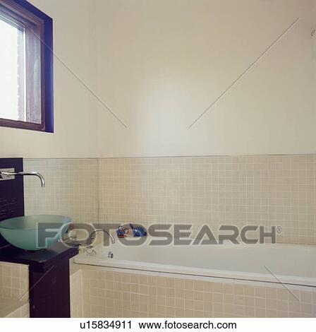Circular glass basin in modern bathroom with neutral mosaic tiling on bath panel and at dado height above bath View Large Photo Image Stock Image - Circular glass basin in modern bathroom with neutral mosaic tiling on bath panel and at dado height above bath. Fotosearch