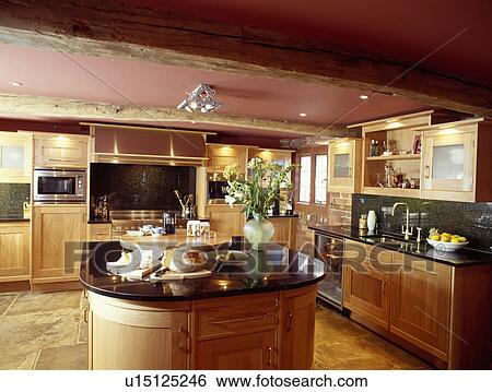 Circular island unit in pink barn conversion kitchen with black granite worktops on pale wood fitted cupboards View Large Photo Image Stock Photograph - Circular island unit in pink barn conversion kitchen with black granite worktops on pale wood fitted cupboards. Fotosearch