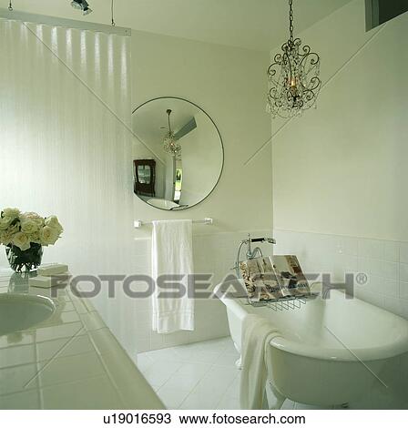 Circular mirror and glass chandelier in modern white bathroom with traditional rolltop bath with bookstand on bathrack View Large Photo Image Stock Image - Circular mirror and glass chandelier in modern white bathroom with traditional rolltop bath with bookstand on bathrack. Fotosearch