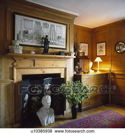 Classical bust in front of pine fireplace with small firescreen in panelled living room View Large Photo Image Stock Photo - Classical bust in front of pine fireplace with small firescreen in panelled living room. Fotosearch