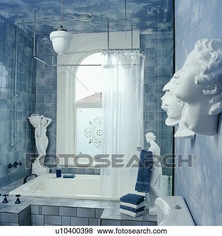 Stock Photo - Classical statues and heads in pastel blue bathroom with blue marbled walls and white shower curtain above bath. Fotosearch