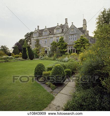 Clipped shrubs on lawn in front of large country house View Large Photo Image Stock Photo - Clipped shrubs on lawn in front of large country house. Fotosearch